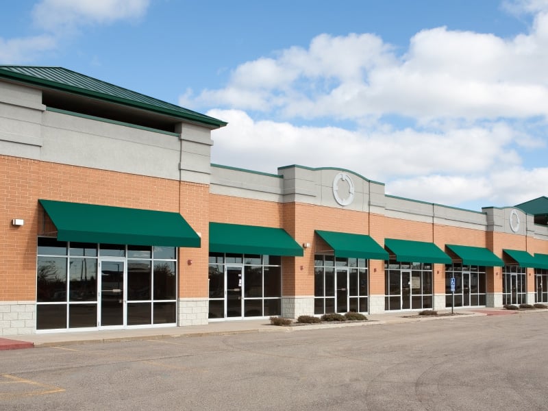 Strip mall retail storefronts with awnings and signage — multi-location sign maintenance for Chicago property managers