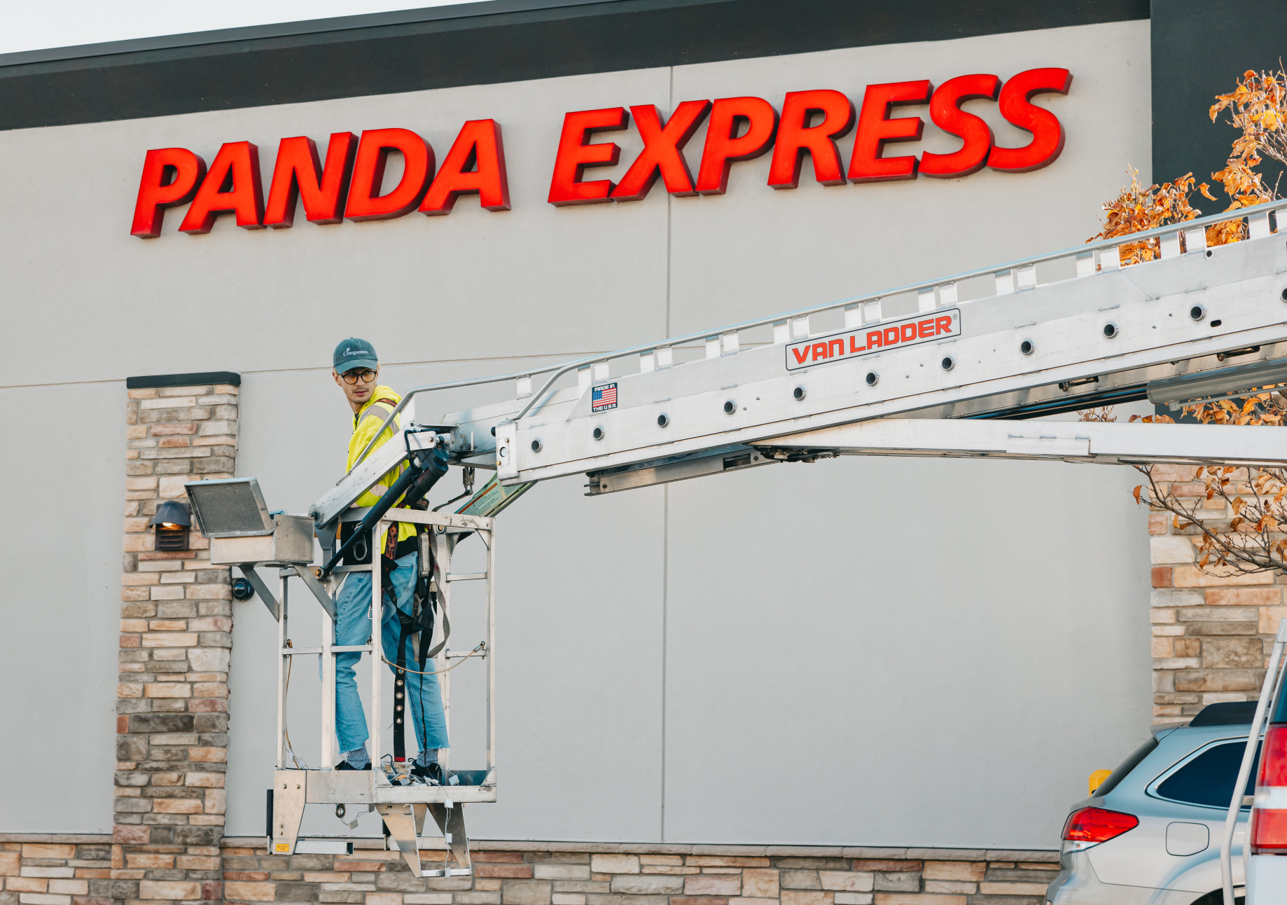 Tymothy Mough of Rick Signs & Repairs in a Van Ladder bucket truck repairing the Panda Express channel letter storefront sign in Chicago