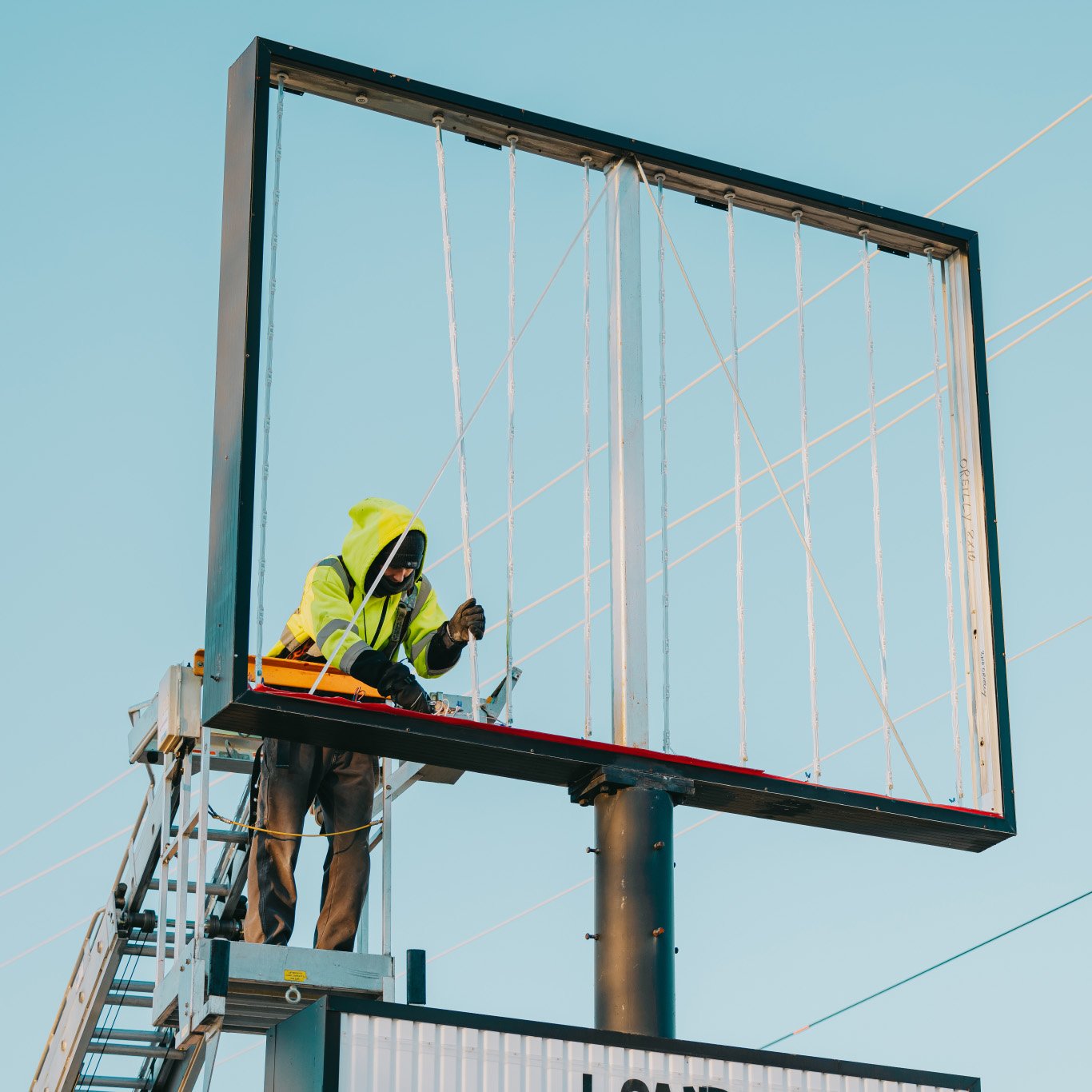 Rick Signs technician on a ladder repairing an illuminated commercial cabinet sign in Chicago