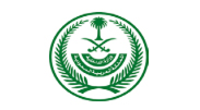 Green emblem with a palm tree, crossed swords, and Arabic script inside a circular wreath.