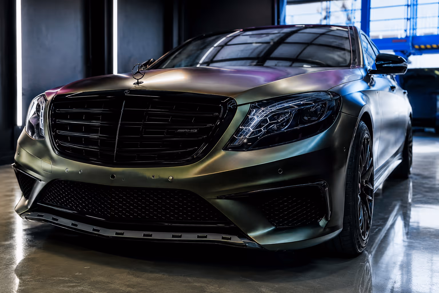 Front view of a black Mercedes-Benz AMG car with detailed headlights and grille in a garage.