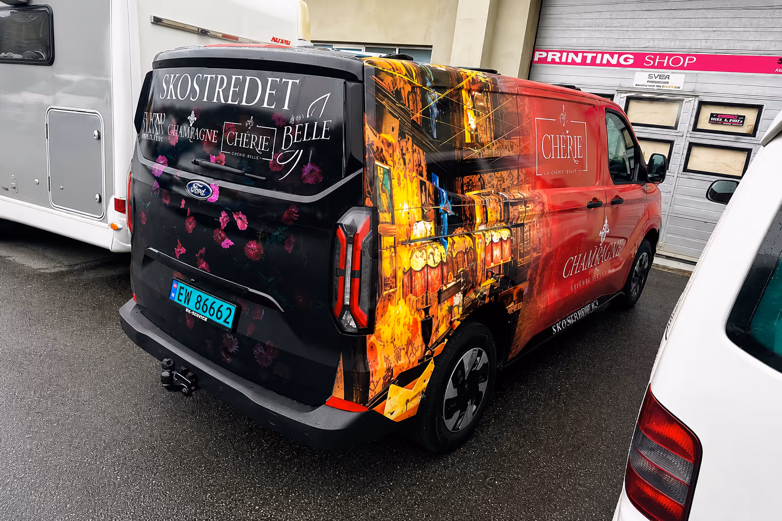 Colorfully wrapped van with floral graphics and advertising text for Skostredet, Chérie, Belle, and Champagne.