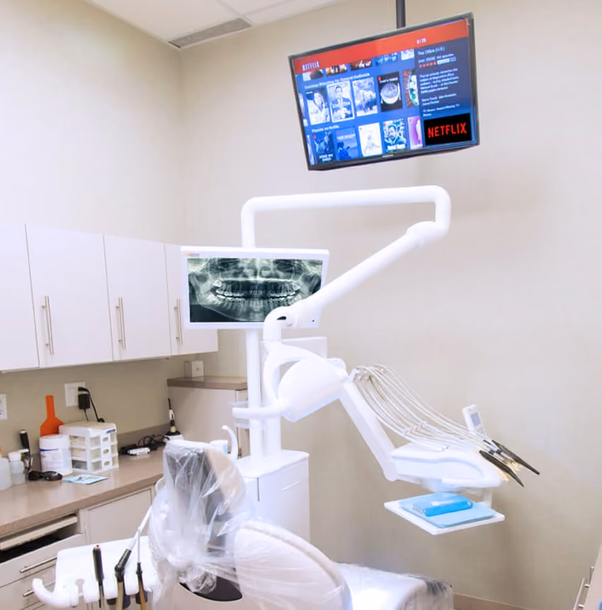 Modern dental office with chair, X-ray screen, and Netflix displayed on a wall-mounted monitor.