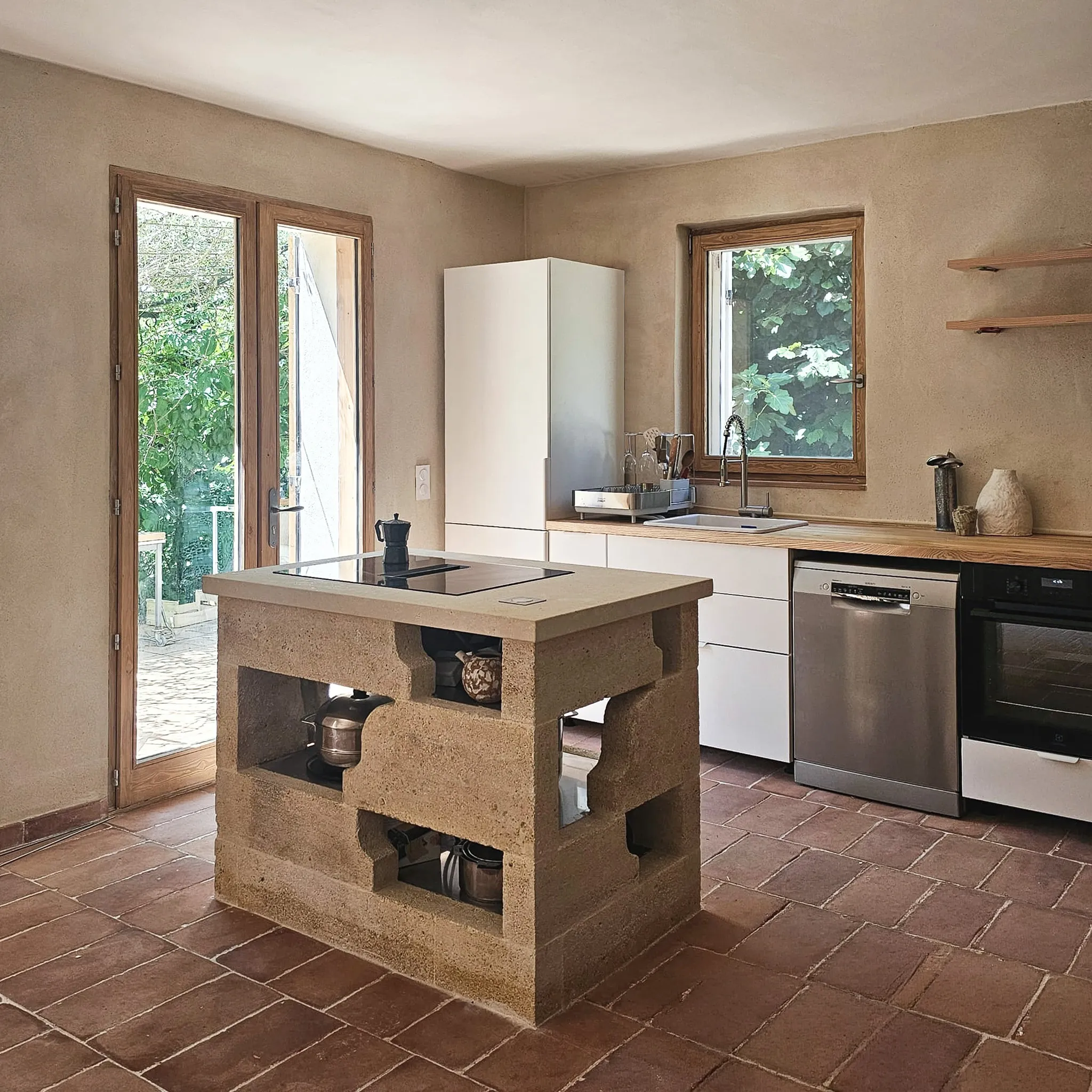 Modern kitchen with stone island cooktop, white cabinets, wooden countertops, and stainless steel appliances.