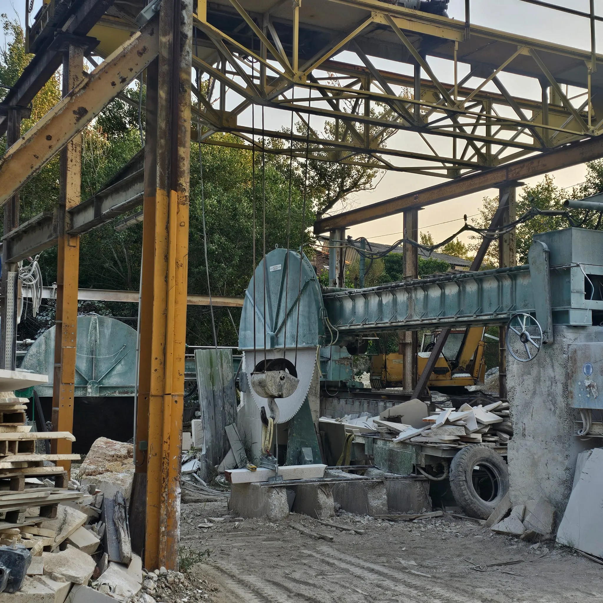 Industrial stone cutting machinery with saw blades, conveyor and stacked stone slabs outdoors.