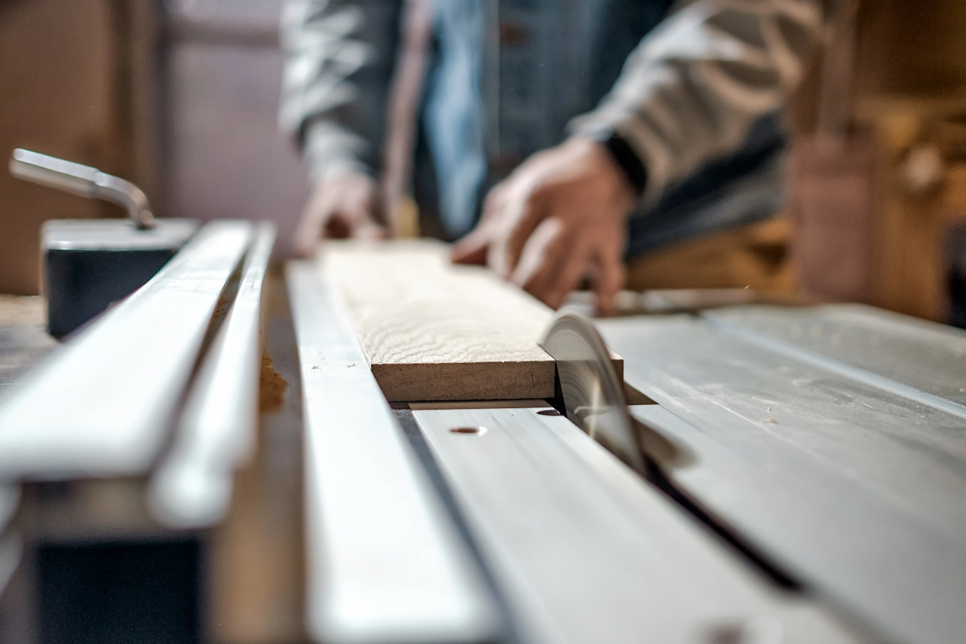 A close-up of a wood saw cutting through a piece of lumber.