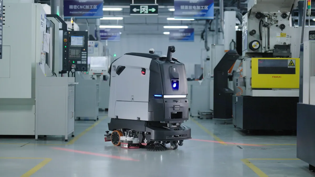 PUDU BG1 curățând aleea unei hale de producție cu utilaje CNC