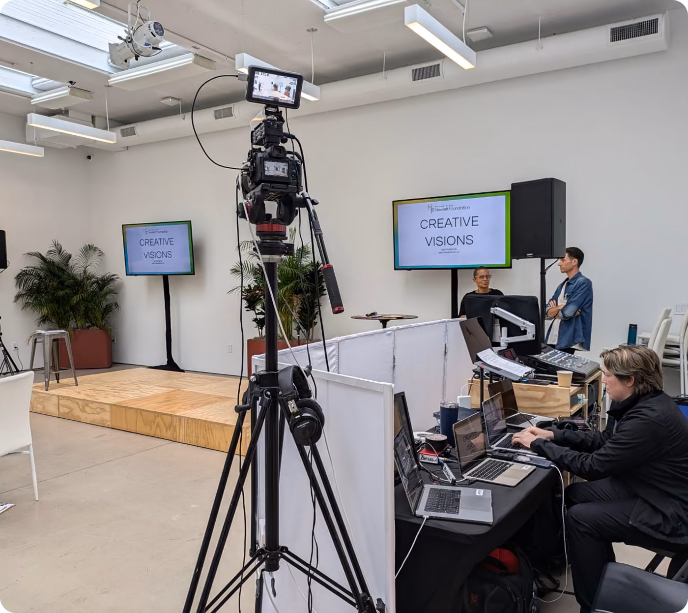 Livestream camera and AV operator at a corporate presentation with TV screens
