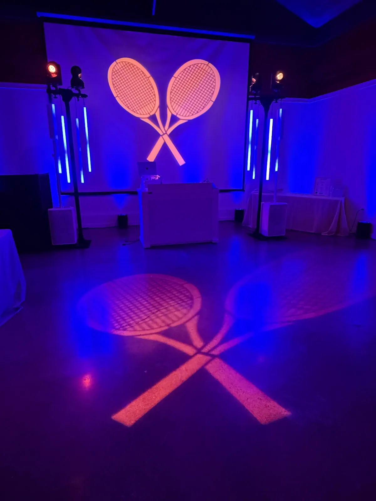Custom crossed-tennis-racket logo projected as a gobo onto the wall and floor