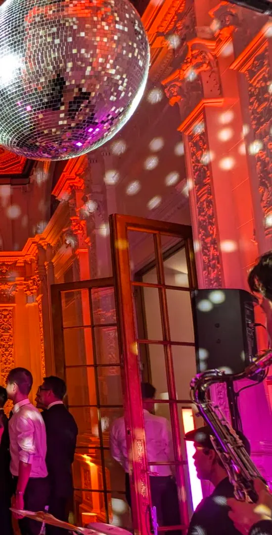 Mirror ball and red and pink event lighting in a room with arched windows