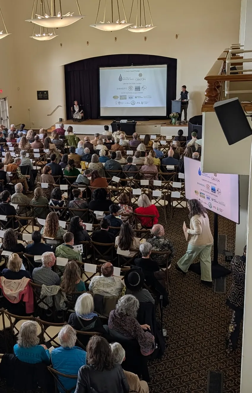 Packed conference hall with a presentation screen, sound and stage lighting
