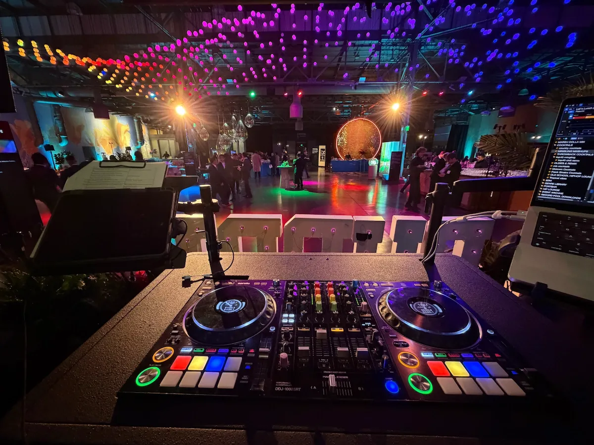 DJ controller in the foreground of a corporate event at the Exploratorium, lit with colorful lights