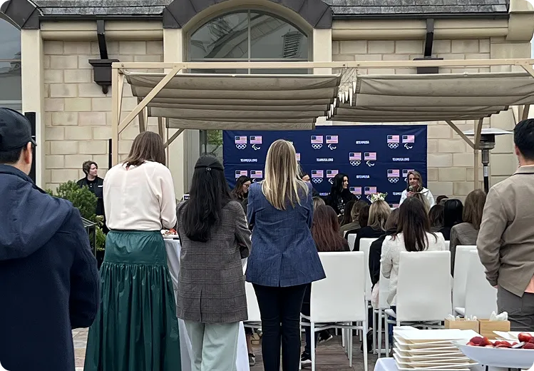 Speakers at an outdoor press event in front of a branded backdrop