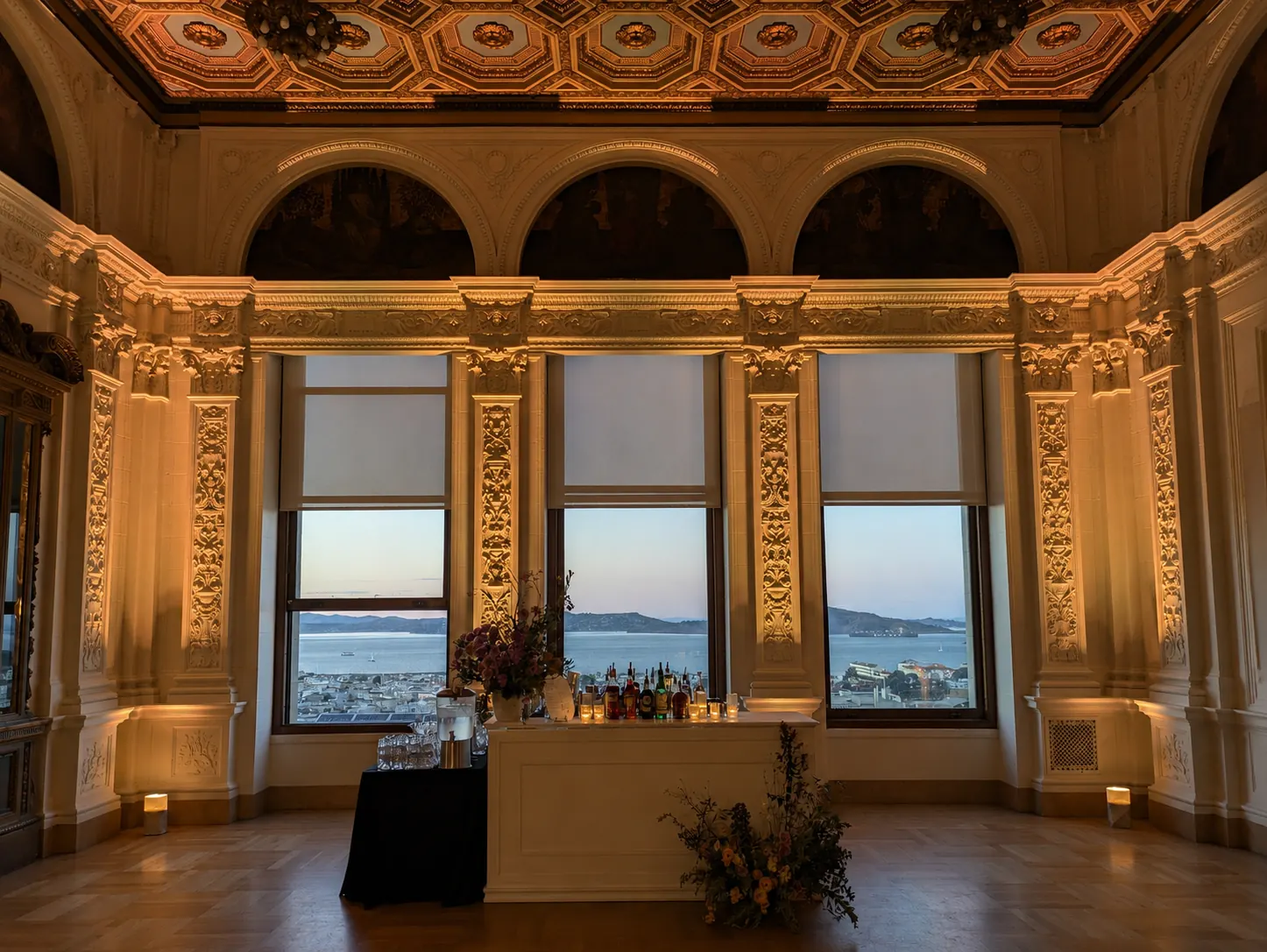 Ornate hall with gilded arches and bay-view windows, lit with warm white uplighting