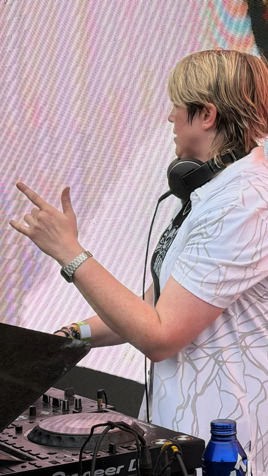 DJ in headphones at the decks in front of a lit backdrop