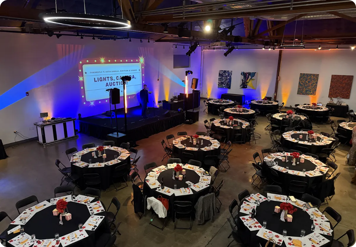 Banquet room with blue uplighting, a presentation screen and round tables