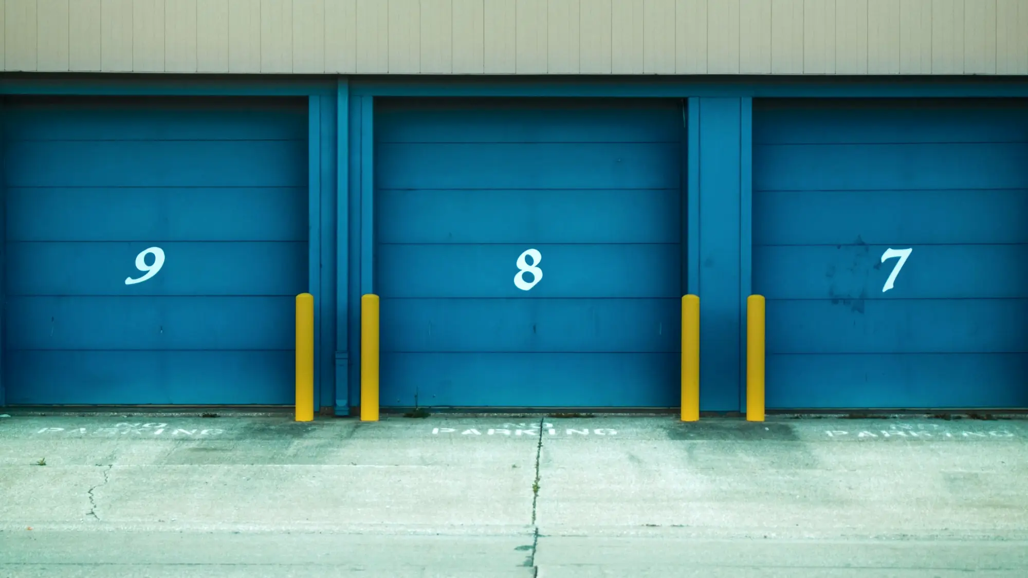 Numbered blue warehouse doors with yellow safety posts in front