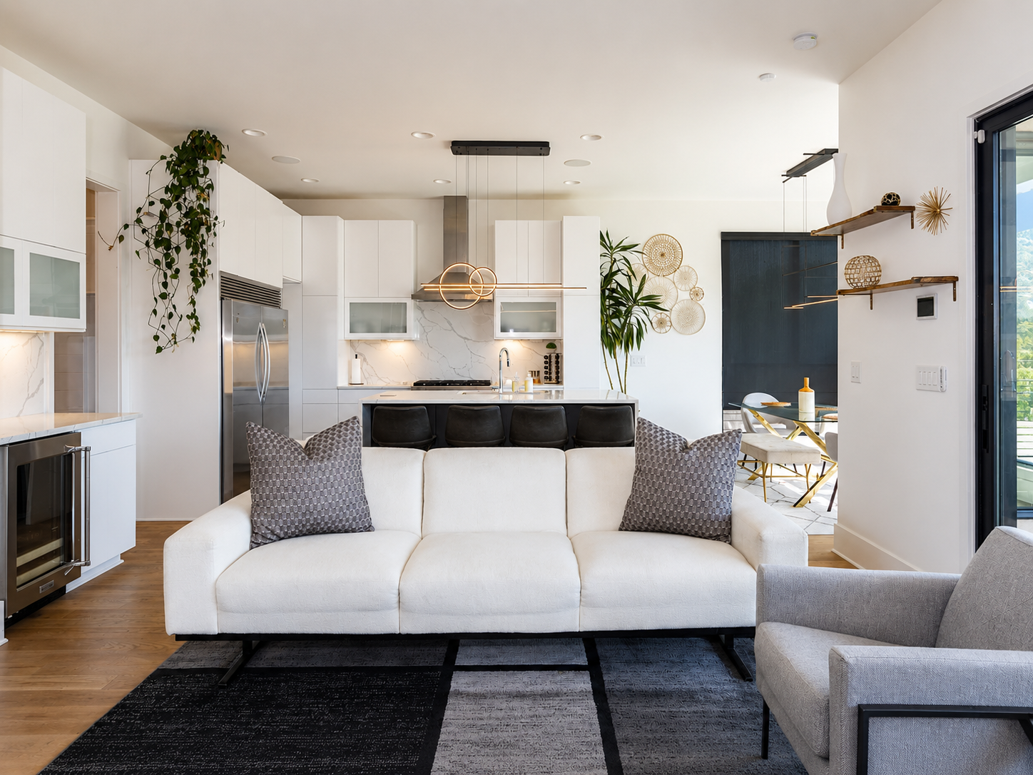 Open-concept white kitchen with a marble-look slab backsplash, large waterfall island, stainless steel appliances, and contemporary lighting in Charlotte, NC.