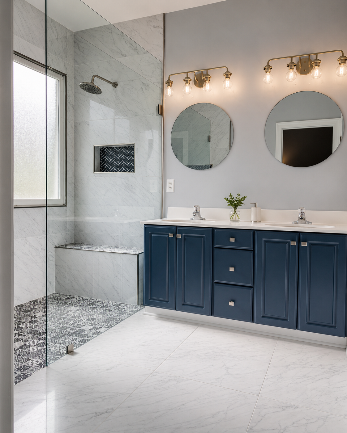 Large walk-in shower with marble-look wall tile, patterned black and white shower floor, tiled bench, dark herringbone niche, and blue vanity in Waxhaw, NC.