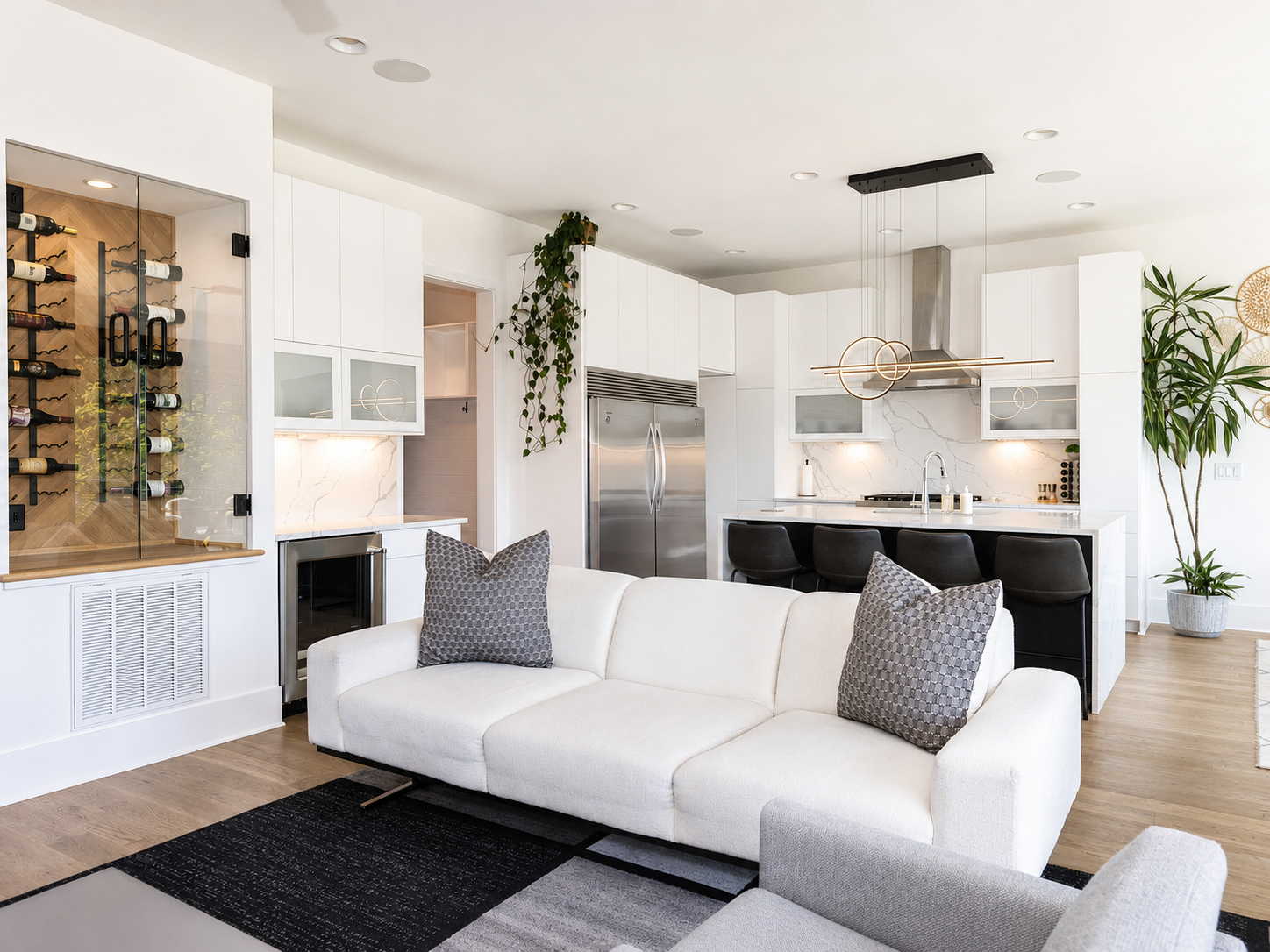 Modern white kitchen with a marble-look slab backsplash, waterfall island, glass-front wine storage, and integrated lighting in Charlotte, NC.