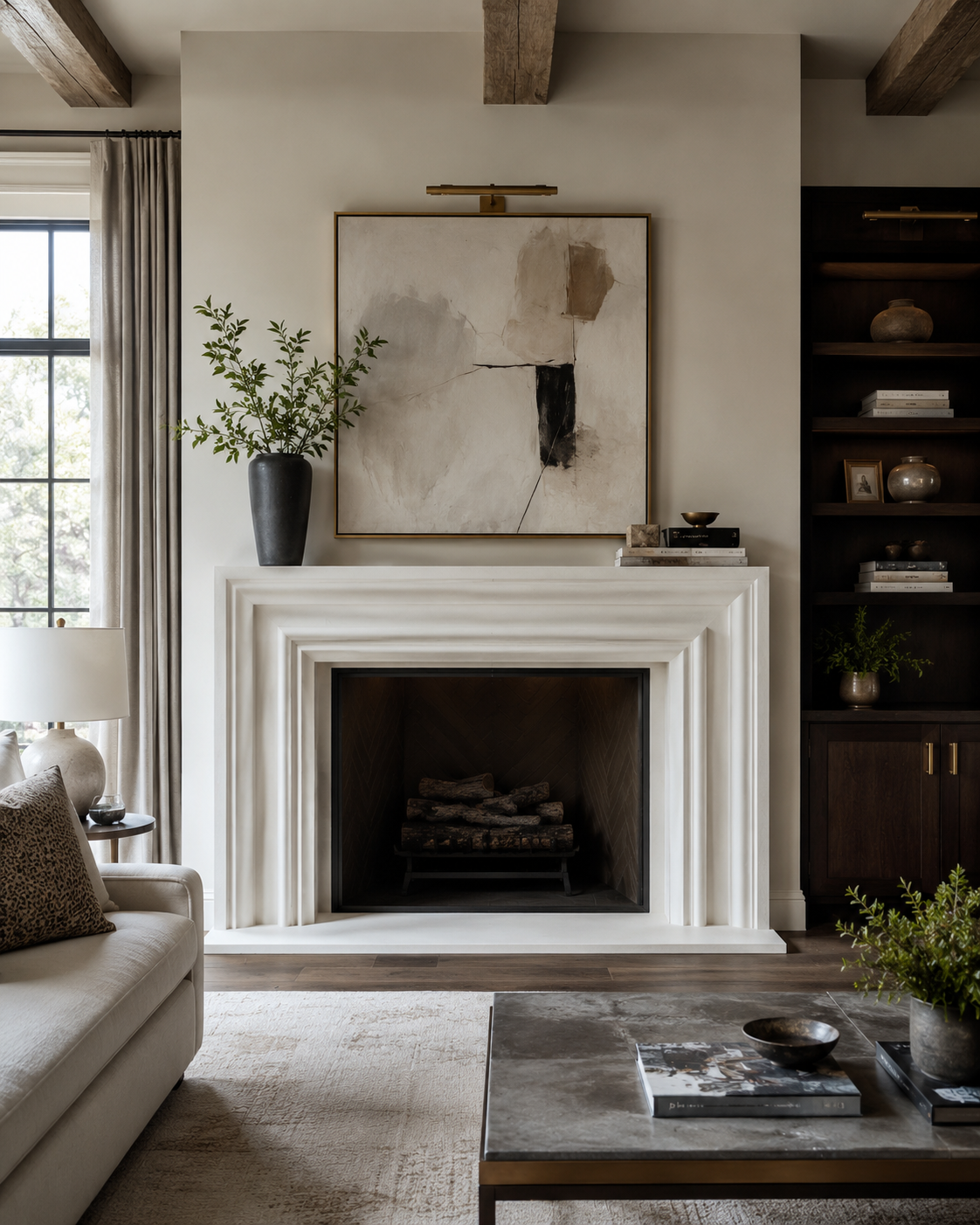 Living room with a layered white precast stone fireplace surround, dark herringbone firebox, exposed wood ceiling beams, and dark built-in shelving in Charlotte, NC