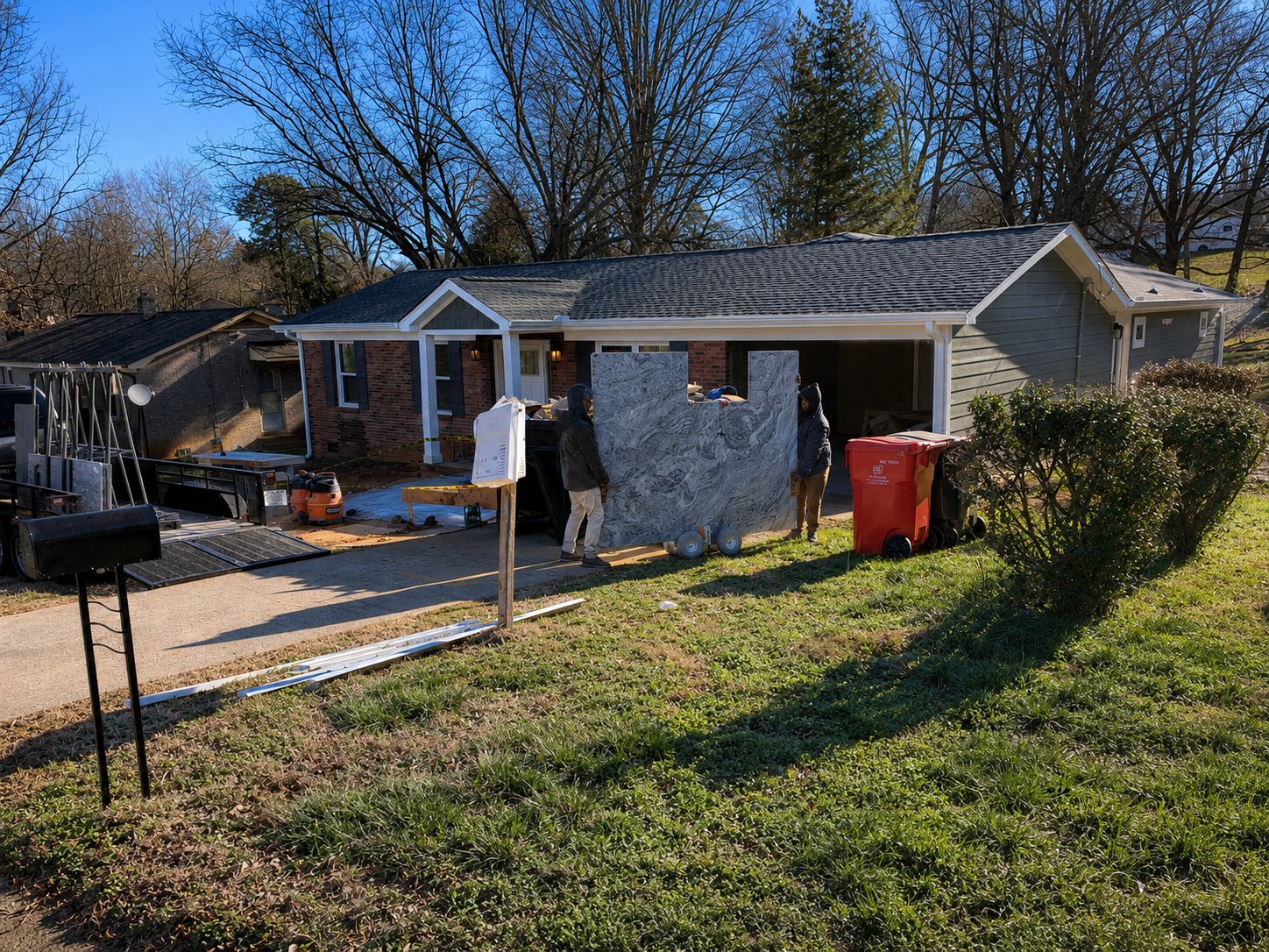 Installation crew transporting a large gray-and-white stone slab from a work trailer toward a residential renovation project in Davidson, NC