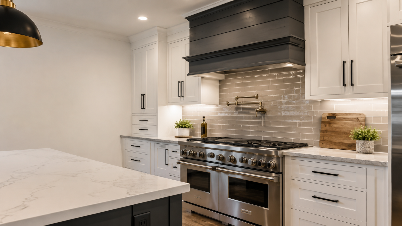Professional kitchen with a glossy greige subway tile backsplash, white shaker cabinets, stainless range, and dark custom hood in Monroe, NC