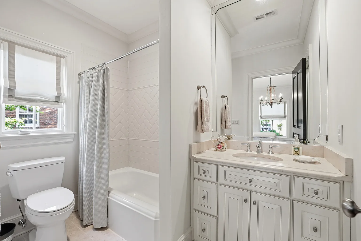 Bright bathroom with a white vanity, bathtub surround, white rectangular wall tile, and a herringbone tile feature panel beneath a window in Harrisburg, NC