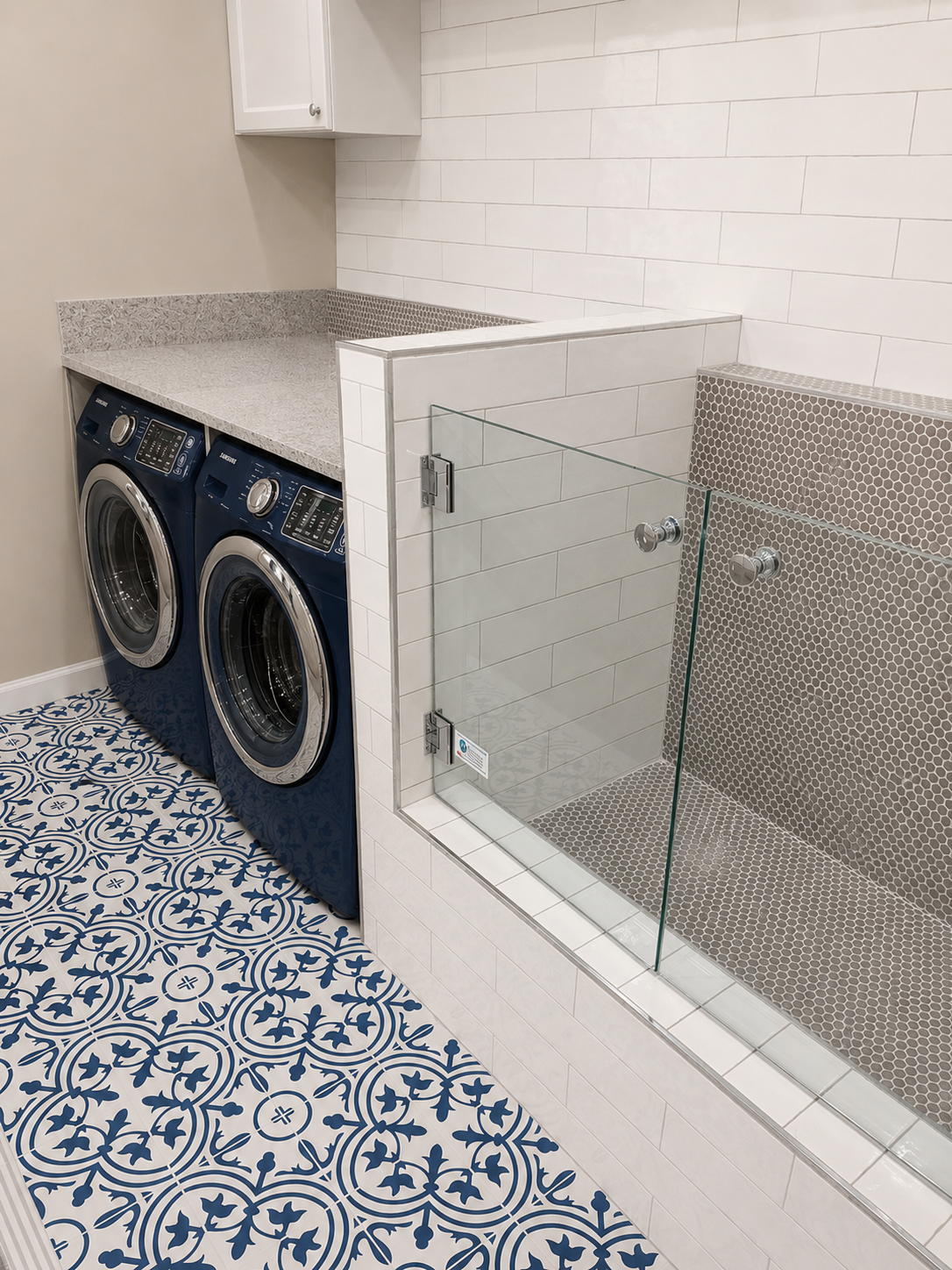 Angled view of a raised tiled dog-wash station with white subway tile, gray penny-round mosaic surfaces, frameless glass splash panels, and patterned laundry-room flooring in Harrisburg, NC