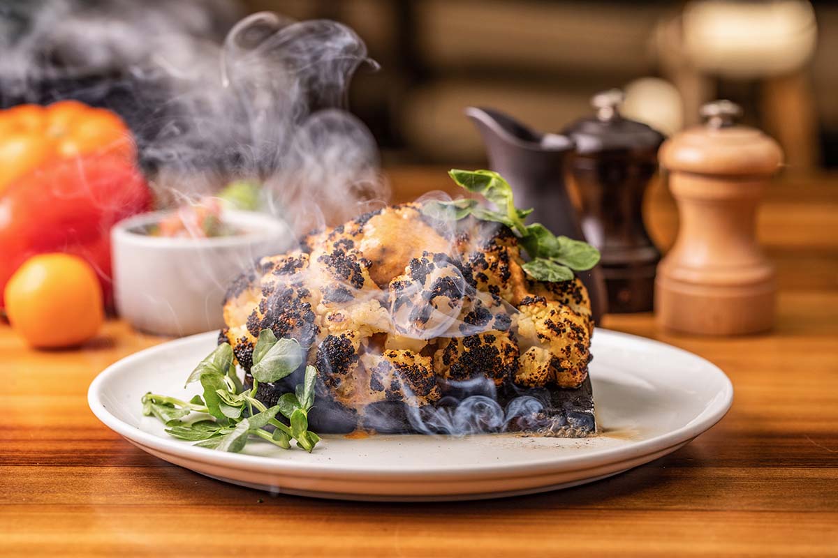 Costilla de res asándose a las brasas en el horno de DANTE Brasa y Fuego