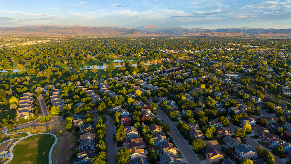 Aerial drone photo of the Fox Meadow neighborhood in Longmont, Colorado, with tree-lined streets and views west to the Front Range.