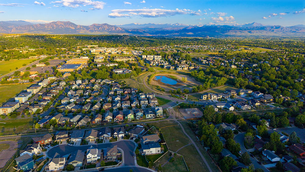 Aerial drone photo of the North End neighborhood in Louisville, Colorado, with open space, a pond, and Front Range views.