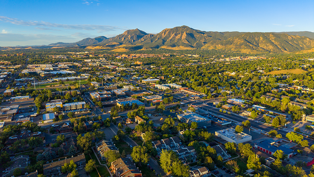 Aerial drone photo of the Glenwood Grove and North Iris neighborhood in Boulder, Colorado, with mature tree canopy, the Iris commercial corridor, and Flatirons views.