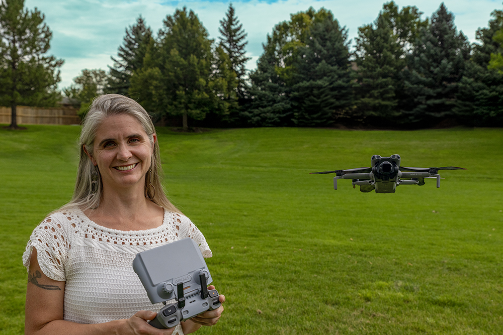 Kyra Coates, founder of Foothills Film + Footage, holding a drone controller in a Boulder County park