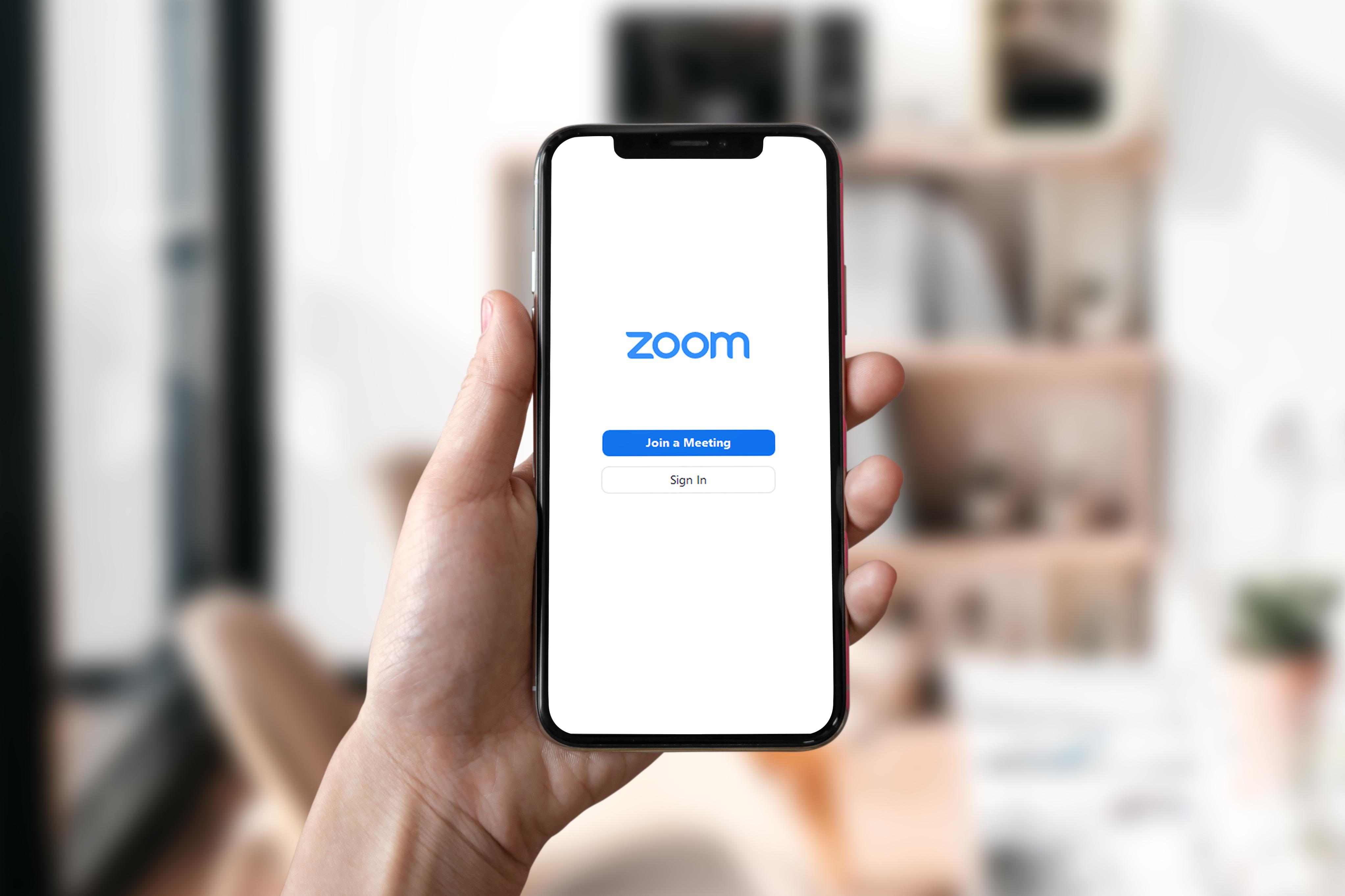 Hand holding mobile phone ready to connect to Zoom. The link takes the user directly to the scheduled Zoom meeting.