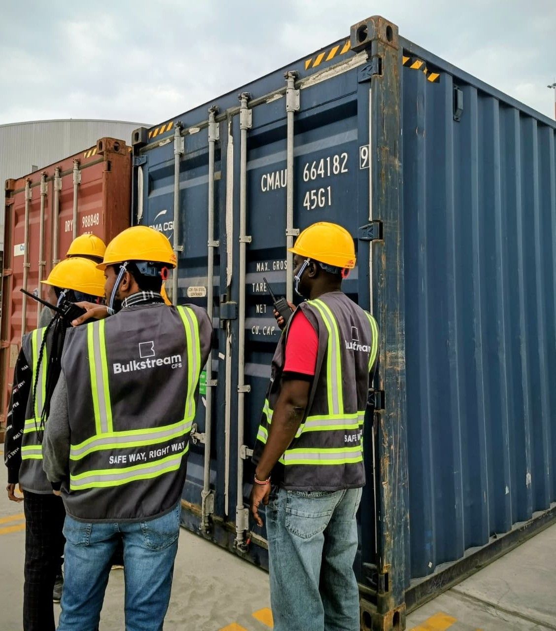 Yard staff with two-way radios beside a shipping container