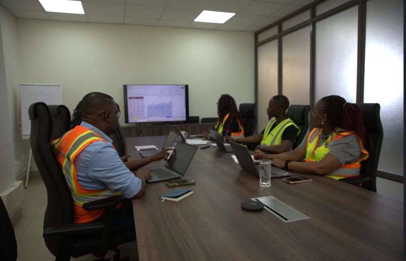 Team at a conference table going through a spreadsheet and chart on a wall screen