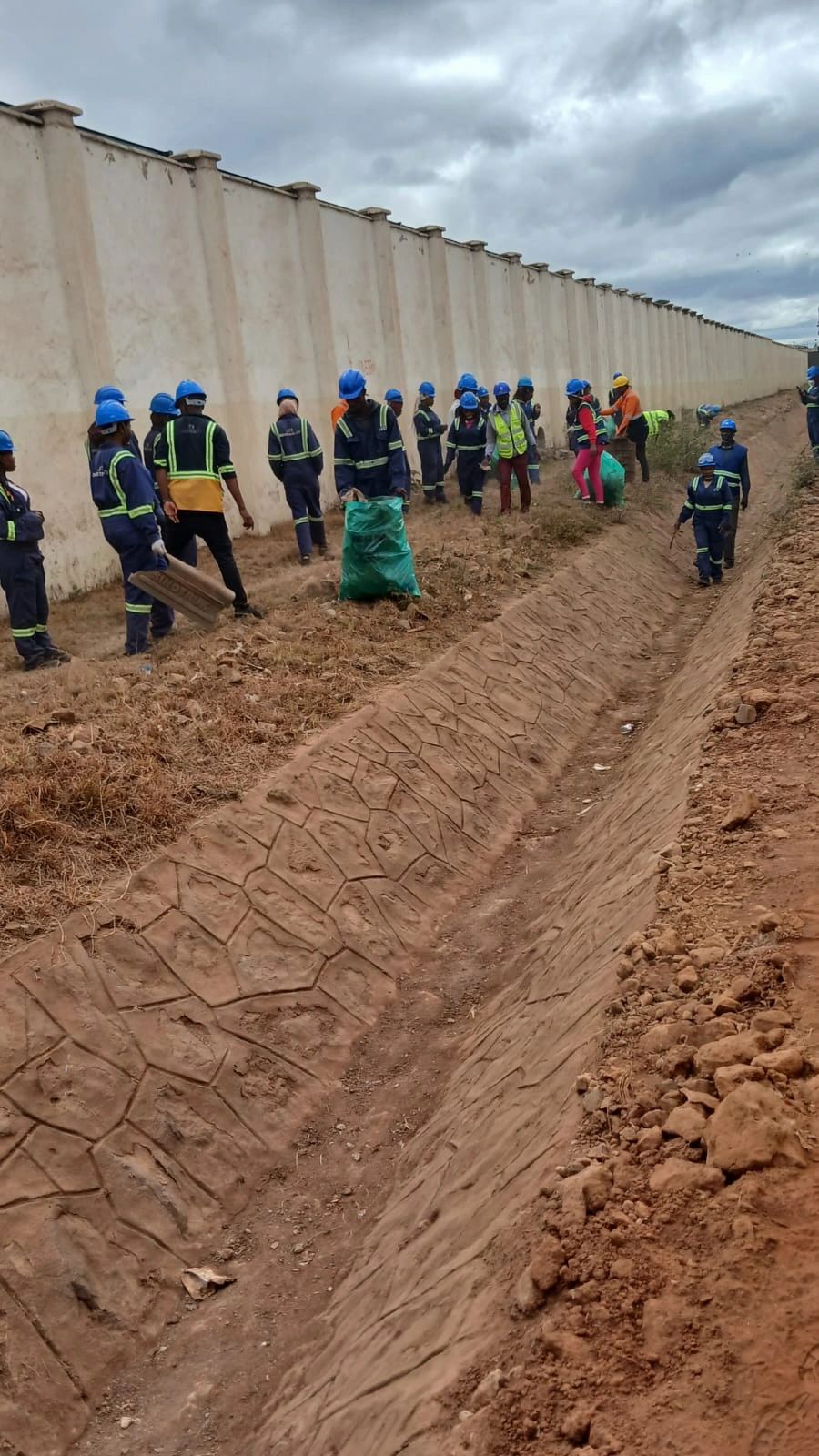 The team collecting litter along the perimeter wall and drainage channel