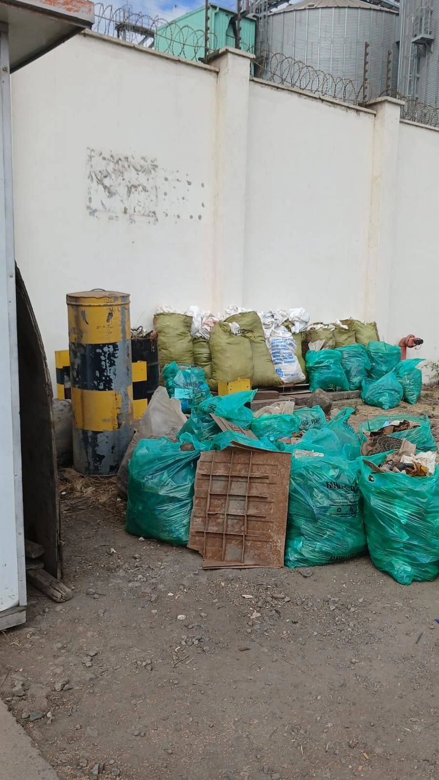 Filled waste bags and sacks gathered against the perimeter wall