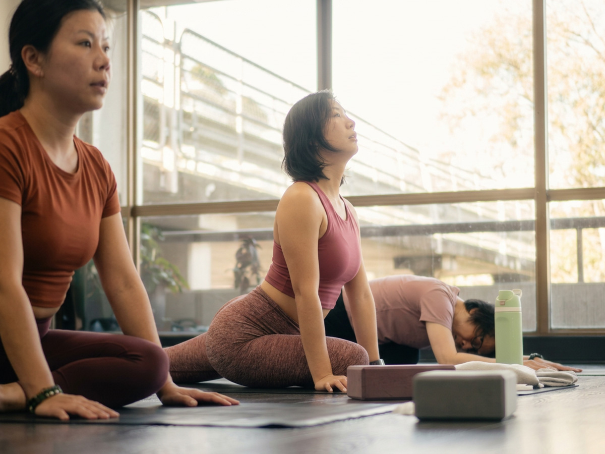 Women practising pigeon pose in a guided yoga and mobility class
