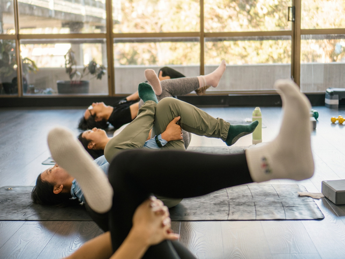 Group mat Pilates class practising hip and hamstring stretches