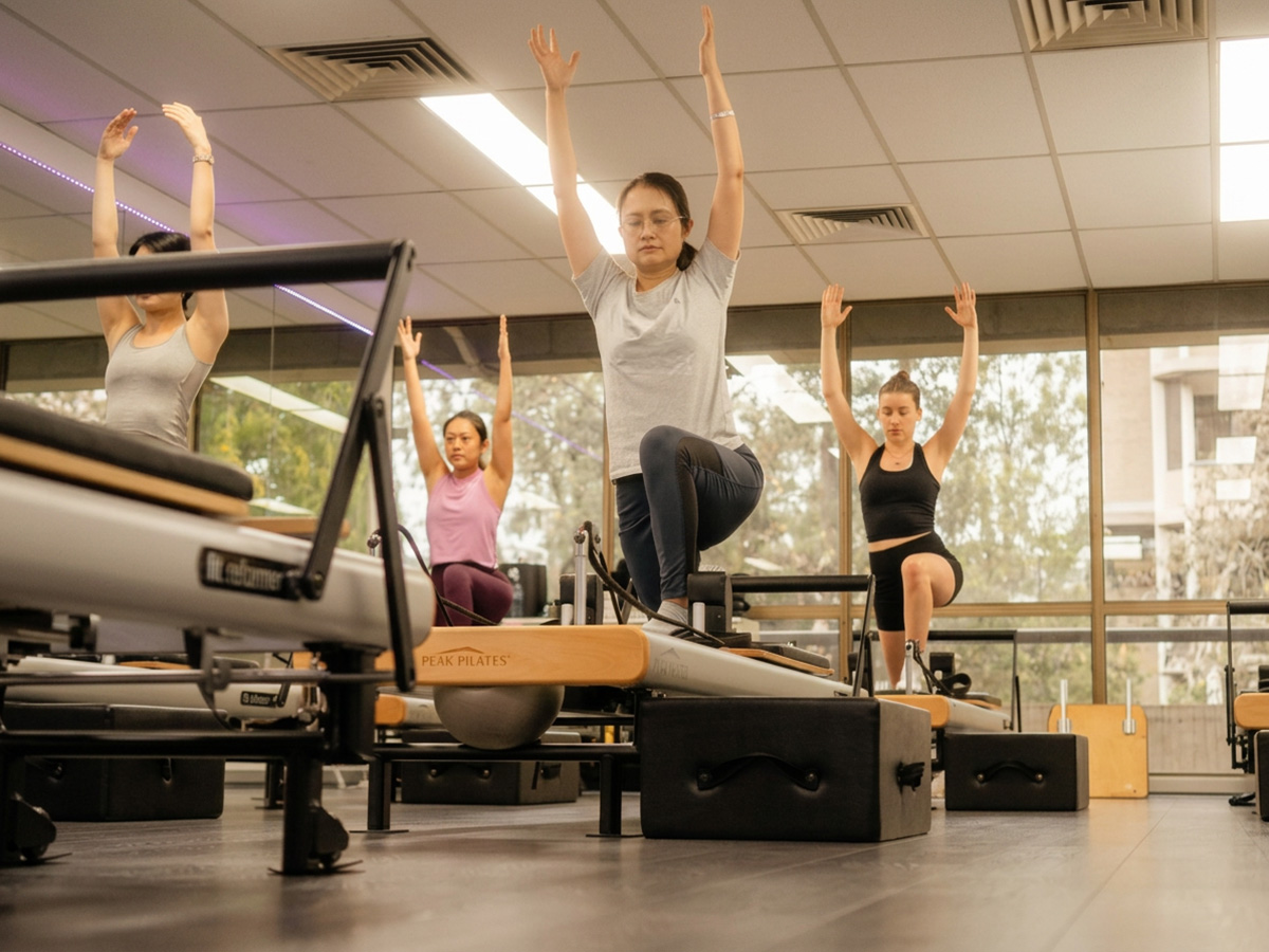 Group reformer Pilates class practising kneeling balance exercises