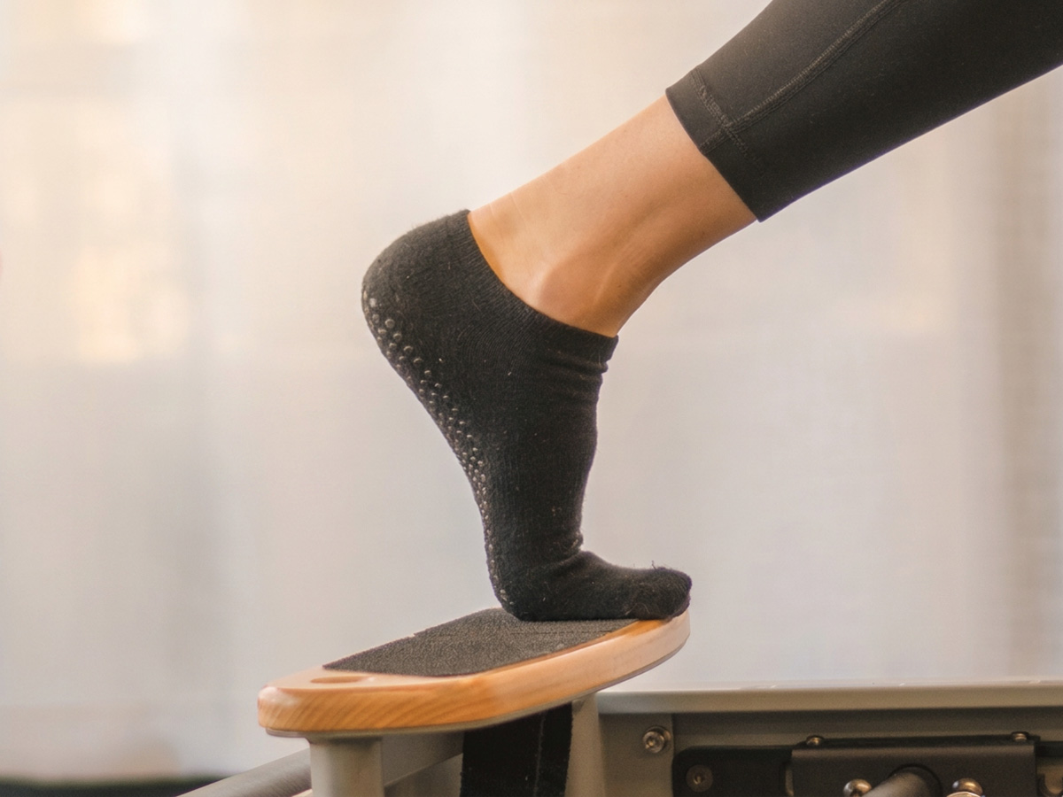 Close-up of a grip sock pressing against a Pilates reformer foot bar