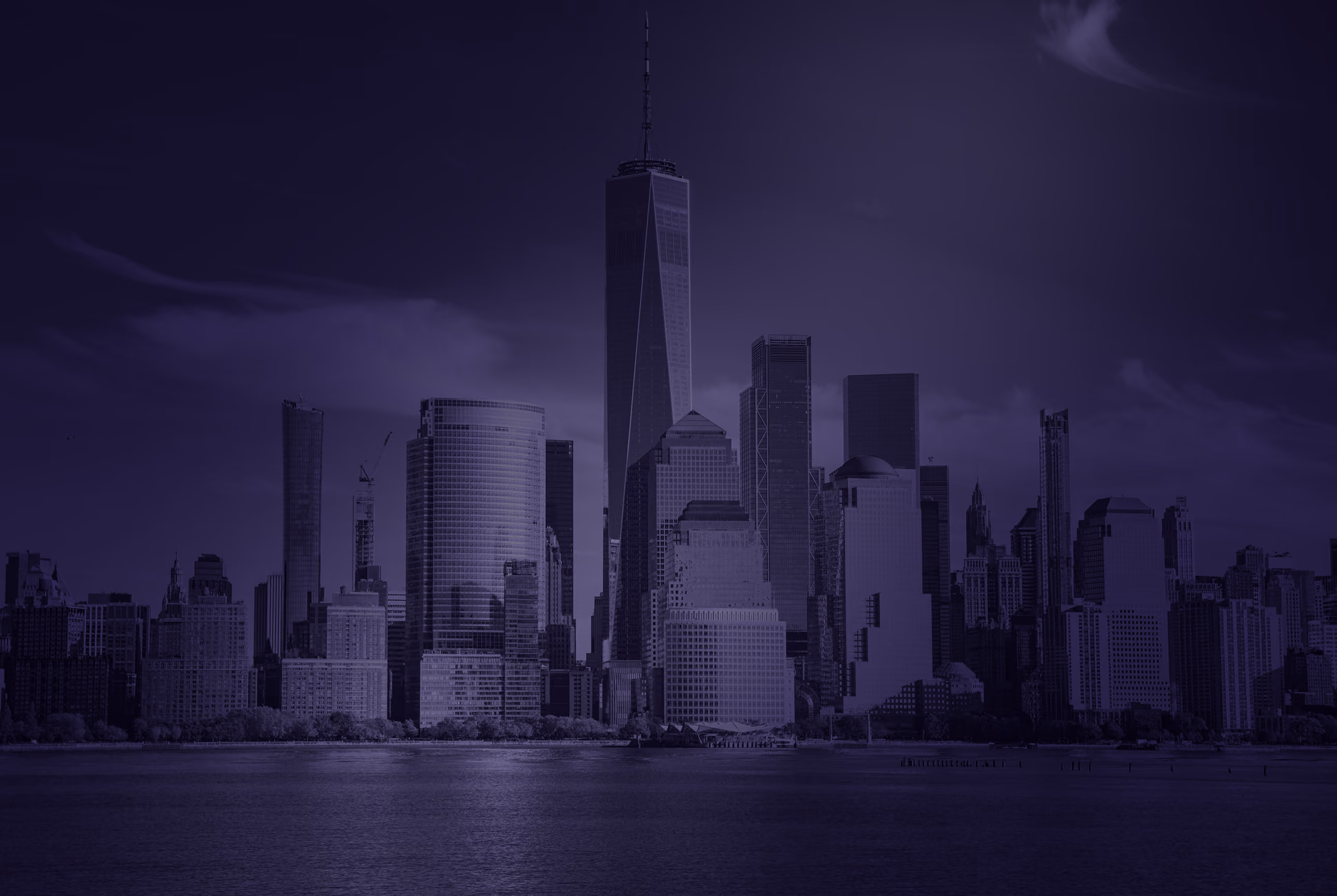 Dusk view of a city skyline with tall modern skyscrapers by the water.