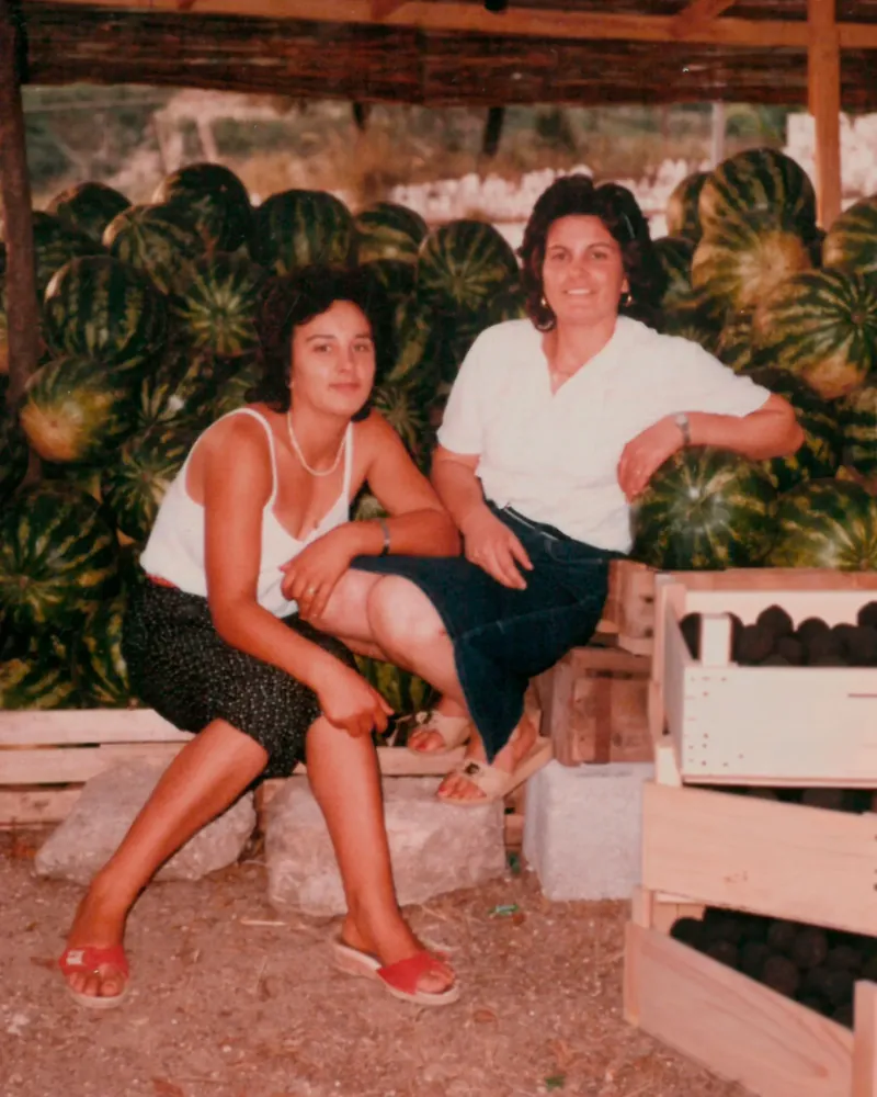 Family photograph of two women seated beside crates of watermelons