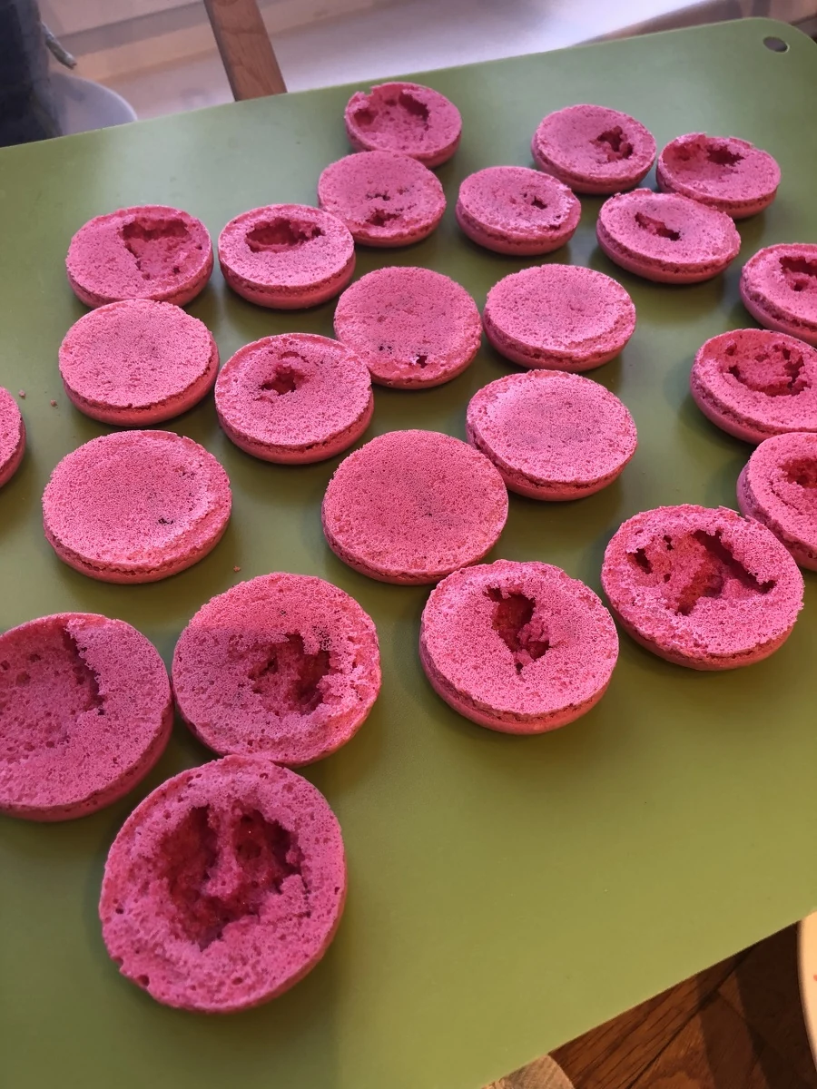 Pink macaron shells turned over, showing torn and uneven bases