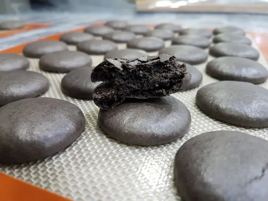 Dark macaron shells with smooth sides and no distinct ruffled feet