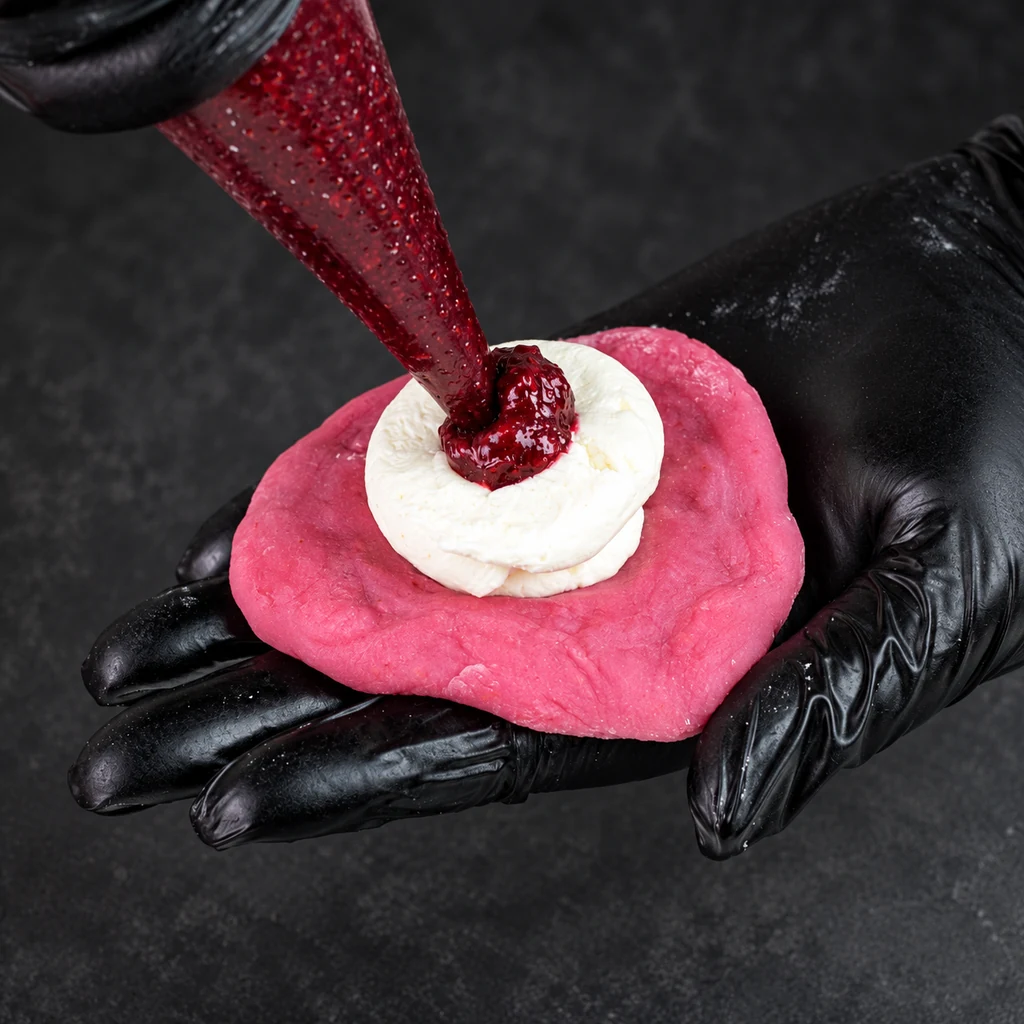 Berry filling piped into cream on a pink mochi wrapper
