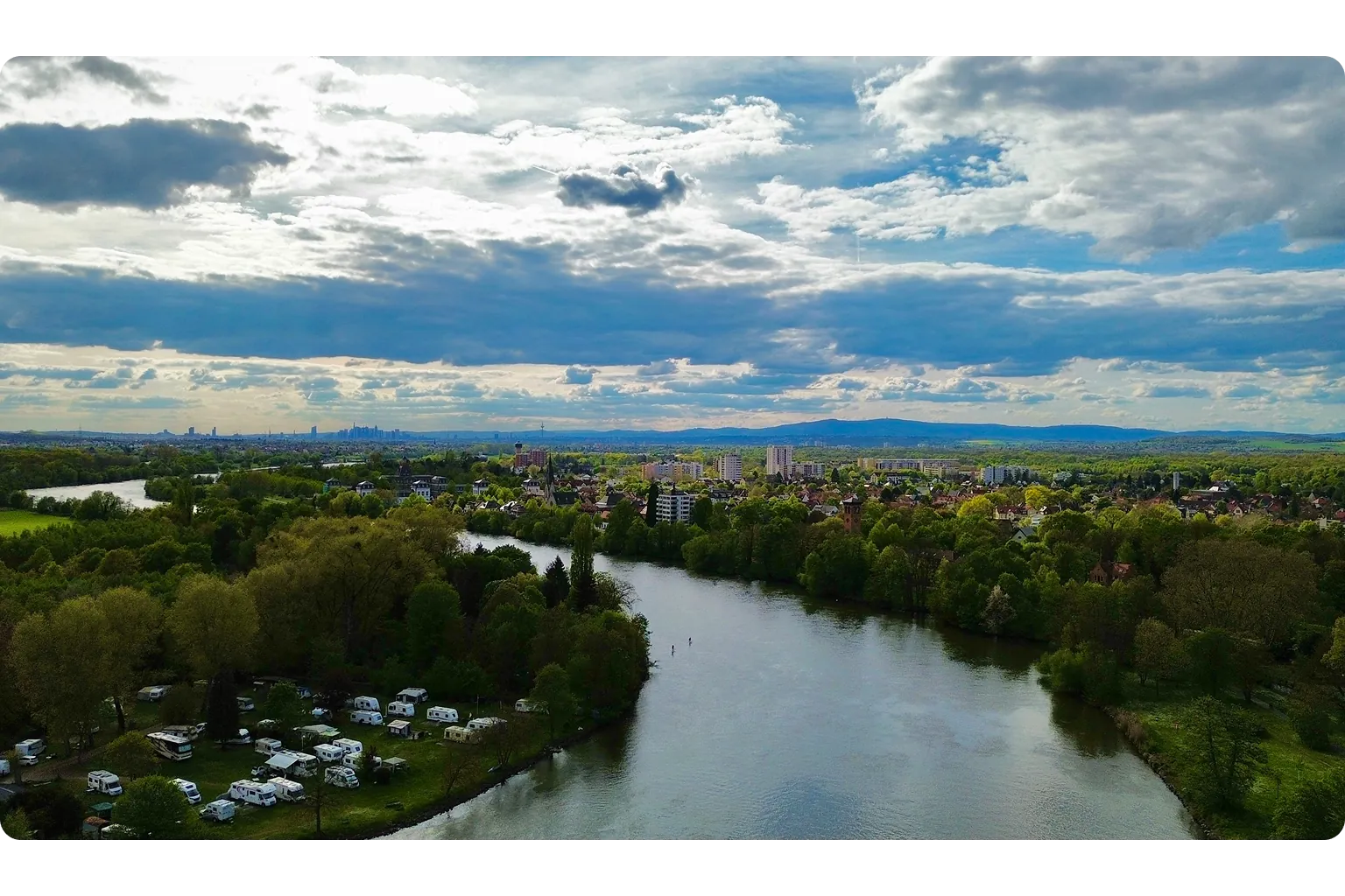 Luftaufnahme des Mains bei Hanau mit grünen Uferlandschaften und Stadtpanorama – externer Datenschutzbeauftragter für Unternehmen in Hanau