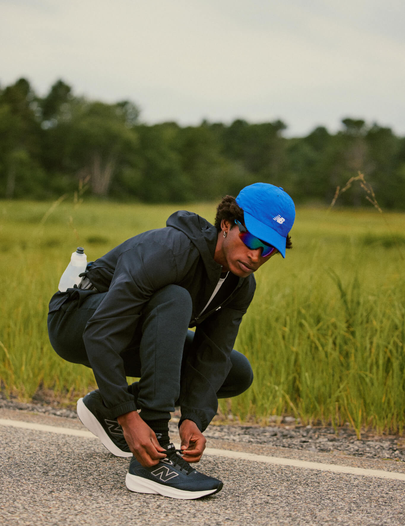 A man wearing New Balance tights his shoe laces.